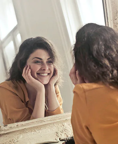 Woman smiling at her reflection in the mirror